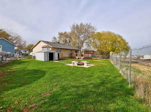 Fenced backyard featuring an outdoor fire pit, a patio area, and a storage unit