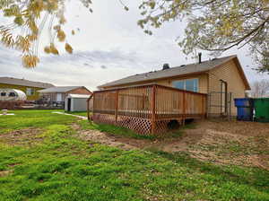 Back of house with a deck and a shed