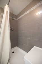 Full bathroom featuring a tile shower and a textured ceiling