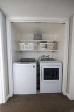 Laundry room with light colored carpet and washing machine and clothes dryer