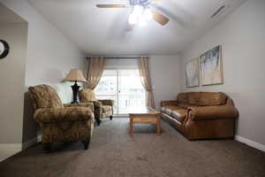 Carpeted living area with baseboards and a ceiling fan