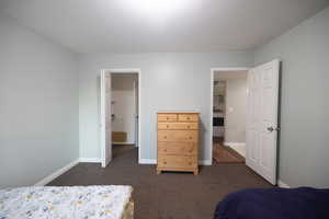 Bedroom featuring dark colored carpet and baseboards