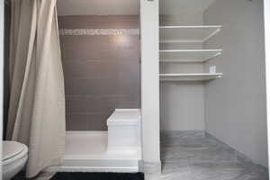 Full bathroom featuring a shower stall, a textured ceiling, and light marble finish floors