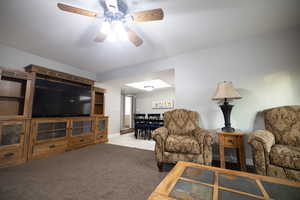 Living area featuring light colored carpet, ceiling fan, and light tile patterned floors