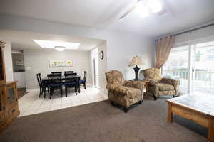 Living room featuring a skylight, light carpet, washer / clothes dryer, and light tile patterned flooring