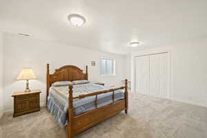 Bedroom featuring light carpet, a closet, and a textured ceiling