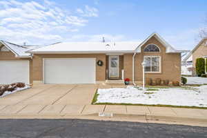 Ranch-style home featuring concrete driveway, a garage, and brick siding