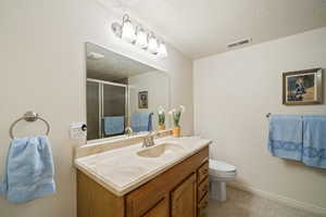 Full bath with vanity, a stall shower, and a textured ceiling