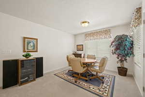 Dining area featuring light colored carpet and a textured ceiling