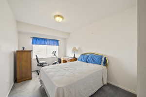 Carpeted bedroom featuring baseboards and an office area