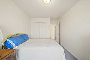Carpeted bedroom featuring a closet and baseboards