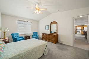 Bedroom featuring lofted ceiling, light carpet, ceiling fan, and freestanding refrigerator