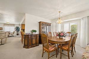 Dining space with light colored carpet and a chandelier