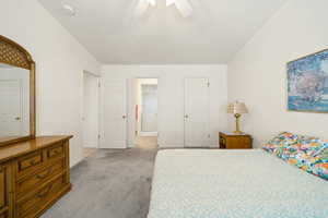 Bedroom with light colored carpet, ceiling fan, and ensuite bathroom