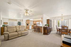 Living room featuring light colored carpet, a chandelier, and ceiling fan