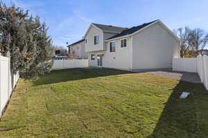 Rear view of house with a fenced backyard and a patio