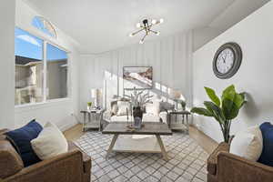 Living area with a chandelier, vaulted ceiling, a decorative wall, and wood finished floors