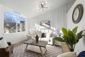 Living room featuring a chandelier, wood finished floors, a decorative wall, and vaulted ceiling