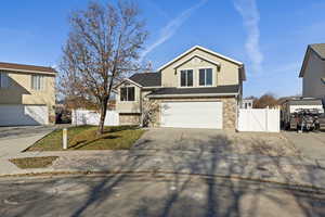 Traditional-style home with a gate, concrete driveway, an attached garage, and stone siding