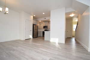 Unfurnished living room with a chandelier, light wood-style flooring, and recessed lighting