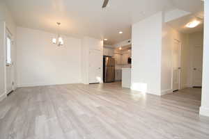 Unfurnished living room with a chandelier, light wood-style flooring, recessed lighting, and a ceiling fan