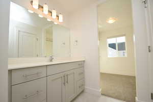 Bathroom with vanity, light colored carpet, and light tile patterned flooring