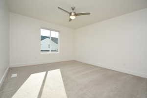 Spare room featuring light carpet and a ceiling fan
