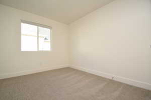 Carpeted spare room with baseboards and lofted ceiling
