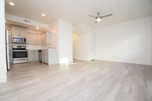 Unfurnished living room with light wood-type flooring, a ceiling fan, and recessed lighting