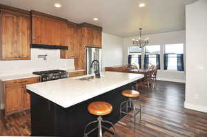 Kitchen featuring a breakfast bar area, decorative light fixtures, a kitchen island with sink, appliances with stainless steel finishes, and a chandelier