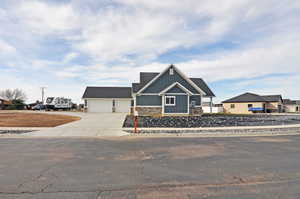 Craftsman inspired home featuring driveway, stone siding, an attached garage, board and batten siding, and a shingled roof