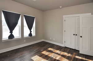 Unfurnished bedroom with a closet and dark wood-type flooring