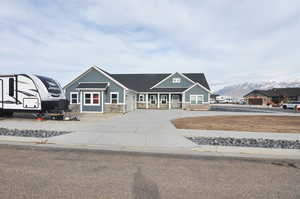 Craftsman house featuring stone siding, driveway, and a porch