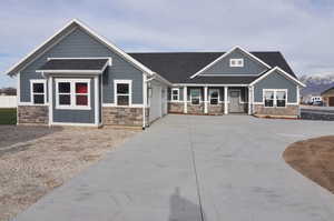 Craftsman-style house with stone siding, board and batten siding, a porch, and a shingled roof