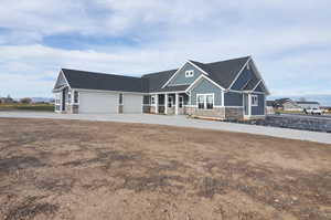 Craftsman house with stone siding, driveway, board and batten siding, and roof with shingles