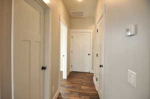 Corridor featuring dark wood-style flooring and baseboards