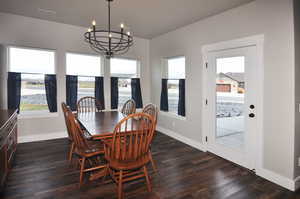 Dining area featuring dark wood-type flooring, a chandelier, and a water view