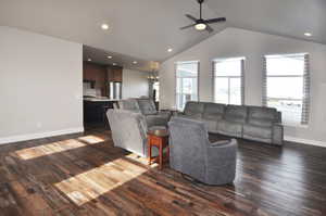Living area featuring dark wood-style flooring, vaulted ceiling, recessed lighting, a ceiling fan, and a chandelier