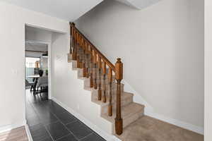 Stairway with baseboards and tile patterned floors