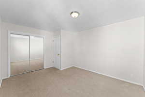 Bedroom featuring light colored carpet, a closet, and a textured ceiling