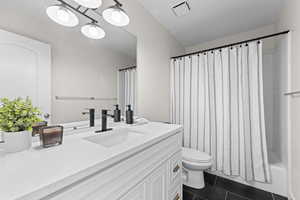 Bathroom with dark tile patterned floors, vanity, and shower / bath combo