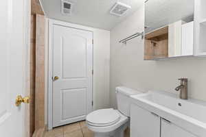 Full bathroom with a textured ceiling, vanity, and light tile patterned floors