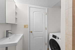 Washroom with washer / clothes dryer and a textured ceiling
