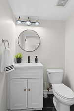 Half bath with vanity and dark tile patterned flooring