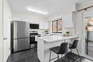 Kitchen featuring appliances with stainless steel finishes, white cabinetry, a peninsula, and a breakfast bar area