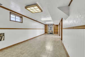 Hall featuring built in features, light tile patterned flooring, and wainscoting