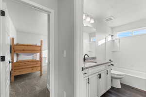 Bathroom featuring vanity, tub / shower combination, a textured ceiling, and dark carpet