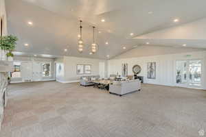 Living area with light colored carpet, a chandelier, recessed lighting, and high vaulted ceiling
