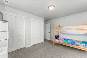 Bedroom featuring two closets and light colored carpet