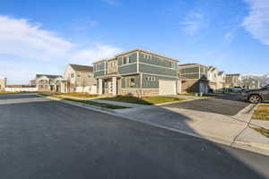 View of front of home featuring a residential view, concrete driveway, stone siding, and a garage